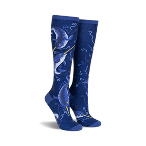 Pair of knee-high socks in navy blue.  Features a whimsical design of narwhals and swirling ocean patterns with subtle shimmer.