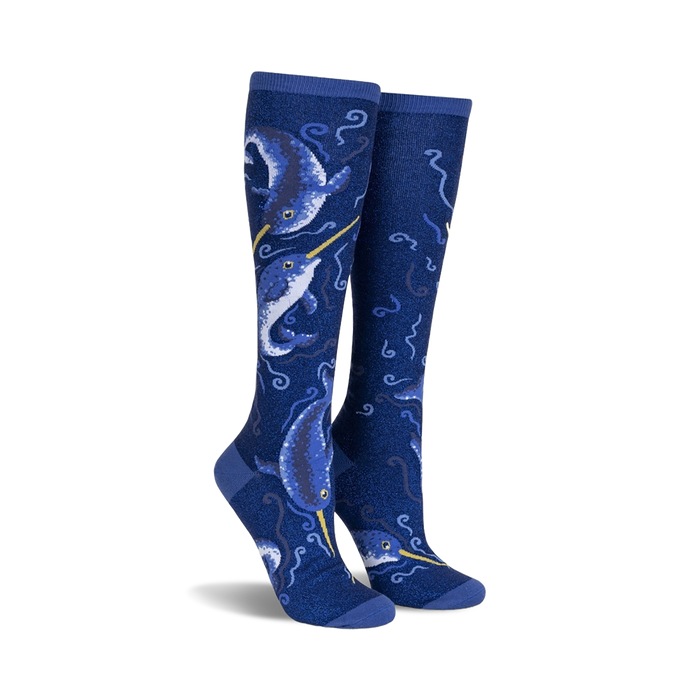 Pair of knee-high socks in navy blue.  Features a whimsical design of narwhals and swirling ocean patterns with subtle shimmer.