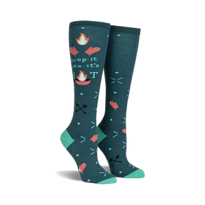Pair of teal knee-high socks with a 'Drop It Like It's Hot' design. Campfire graphics, flaming hearts, and crossed utensils are featured on a teal background.