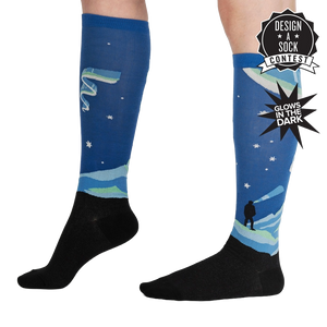 Lifestyle shot of the Northern Lights glow-in-the-dark socks on a model's legs, showcasing their length and design.