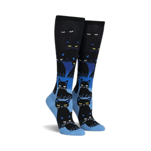 Pair of black and blue knee-high socks with a repeating pattern of black cats. The cats glow in the dark, and the socks have a gradient design.