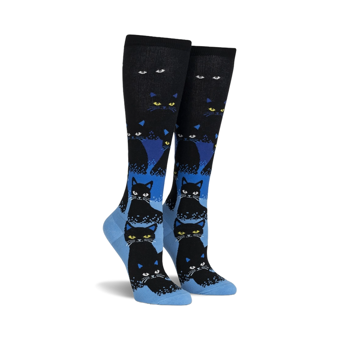 Pair of black and blue knee-high socks with a repeating pattern of black cats. The cats glow in the dark, and the socks have a gradient design.
