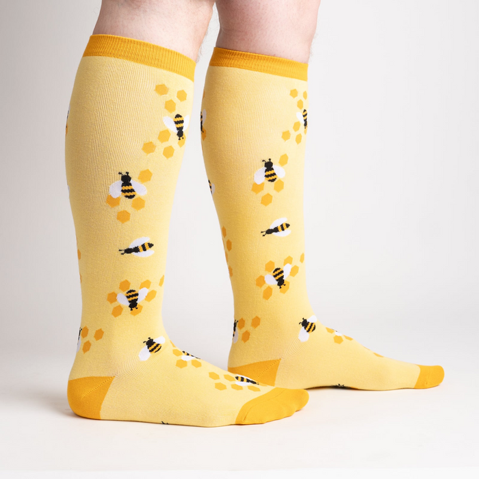 Lifestyle shot of model wearing yellow bee socks, showcasing fit and style.