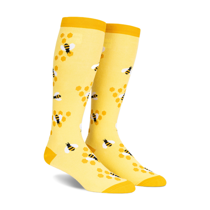 Pair of yellow knee-high socks with a pattern of black and white bees on honeycombs.