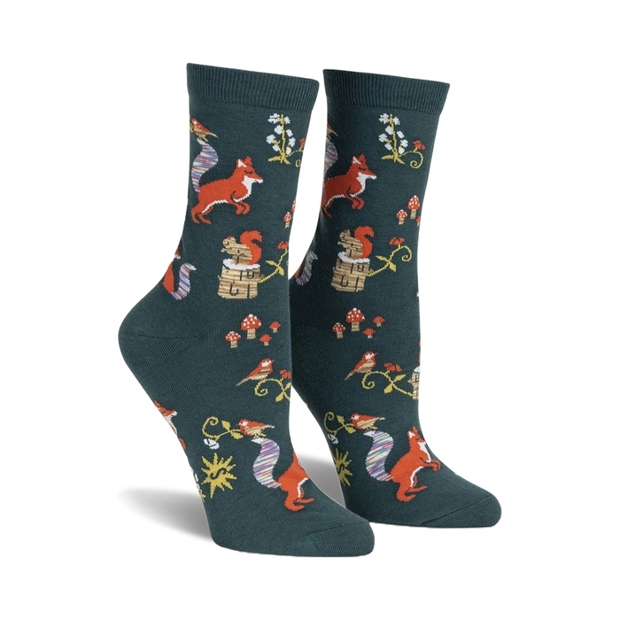 Pair of women's crew socks. Dark teal background with repeating pattern of foxes, squirrels, birds, mushrooms, and flowers.