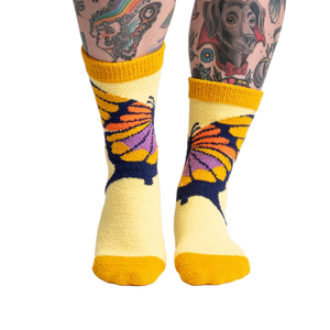 Lifestyle shot of a person wearing the yellow butterfly slipper socks, showcasing the fit and feel.