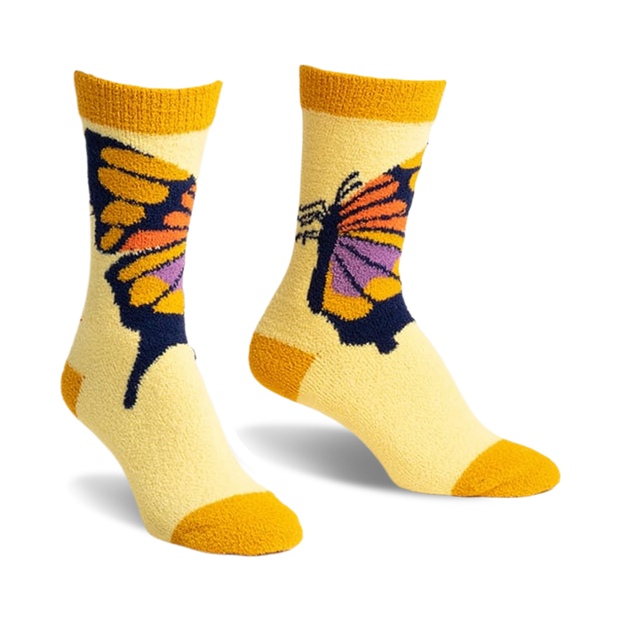 Pair of yellow cozy slipper socks with a colorful butterfly design. The butterfly is orange, purple, and dark blue on a pale yellow background with mustard yellow cuffs.