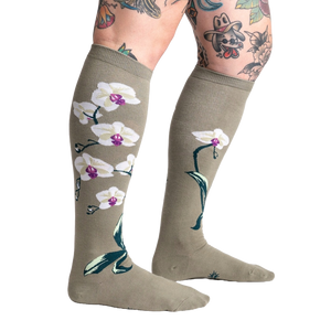 Light olive green knee socks with a repeating pattern of white orchids with purple centers and green stems and leaves.