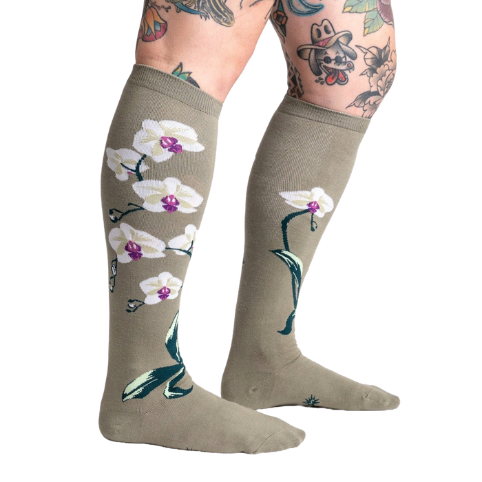 Light olive green knee socks with a repeating pattern of white orchids with purple centers and green stems and leaves.