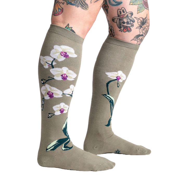 Lifestyle shot showcasing Orchid knee-high socks on a model with tattoos, highlighting the socks' length and design.