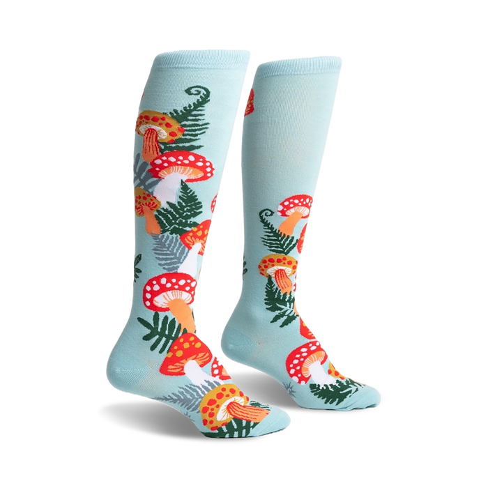 Pair of pastel blue knee-high socks adorned with a whimsical pattern of red and orange mushrooms and green ferns.
