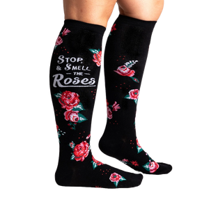 A pair of black knee-high socks with a red and pink floral pattern and the words 