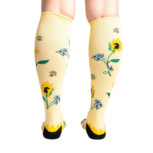 Rear view of the socks on a person's legs, showcasing the back of the sunflower design.