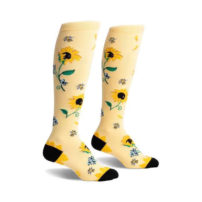 Pair of knee-high socks in pale yellow with a sunflower, bee, and floral design. Black heel and toe.