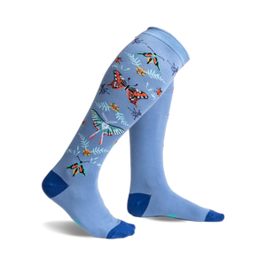 A pair of light blue knee-high socks adorned with colorful butterflies, ladybugs, and floral accents.