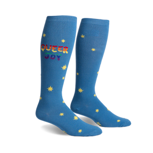 Pair of blue knee-high socks.  Rainbow 'Queer Joy' text and yellow star pattern.