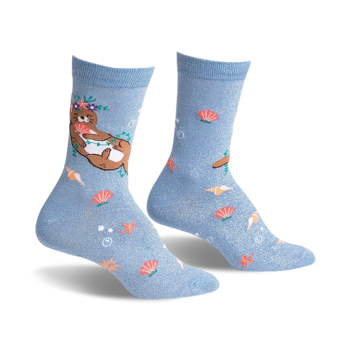 Pair of light blue crew socks with a whimsical design.  Features a flower-crowned otter, seashells, starfish, and subtle shimmer.