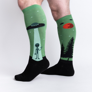 Lifestyle shot of a person wearing the 'I Believe' alien-themed knee-high socks.