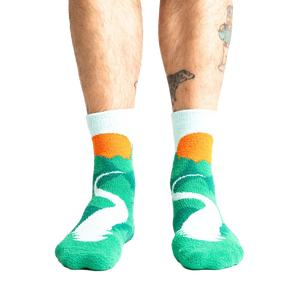 Lifestyle shot of a person's legs wearing the teal and light blue mountain slipper socks.