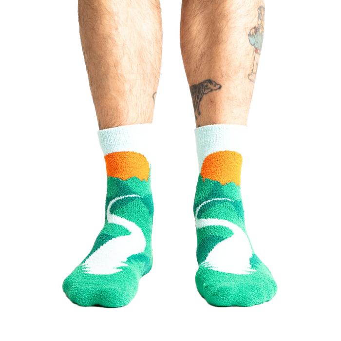 Lifestyle shot of a person's legs wearing the teal and light blue mountain slipper socks.
