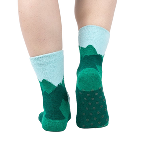 Back view of a person's legs wearing the teal and light blue mountain slipper socks, showcasing the non-slip soles.