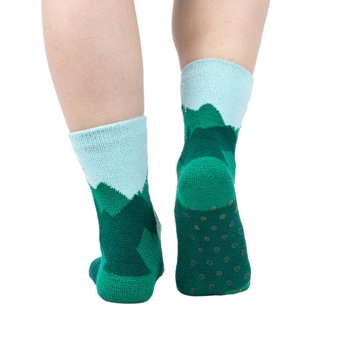 Back view of a person's legs wearing the teal and light blue mountain slipper socks, showcasing the non-slip soles.