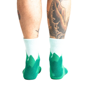 Back view of a person's legs wearing the teal and light blue mountain slipper socks, showcasing the non-slip soles.