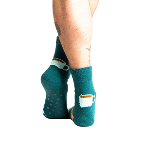Back view of model wearing teal blue coffee and croissant slipper socks.
