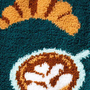 Detailed close-up of the coffee and croissant design on the teal blue slipper socks.