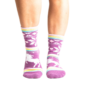 Lifestyle shot: Woman's legs wearing purple unicorn slipper socks.