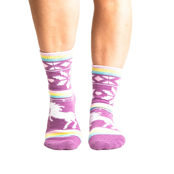 Lifestyle shot: Woman's legs wearing purple unicorn slipper socks.