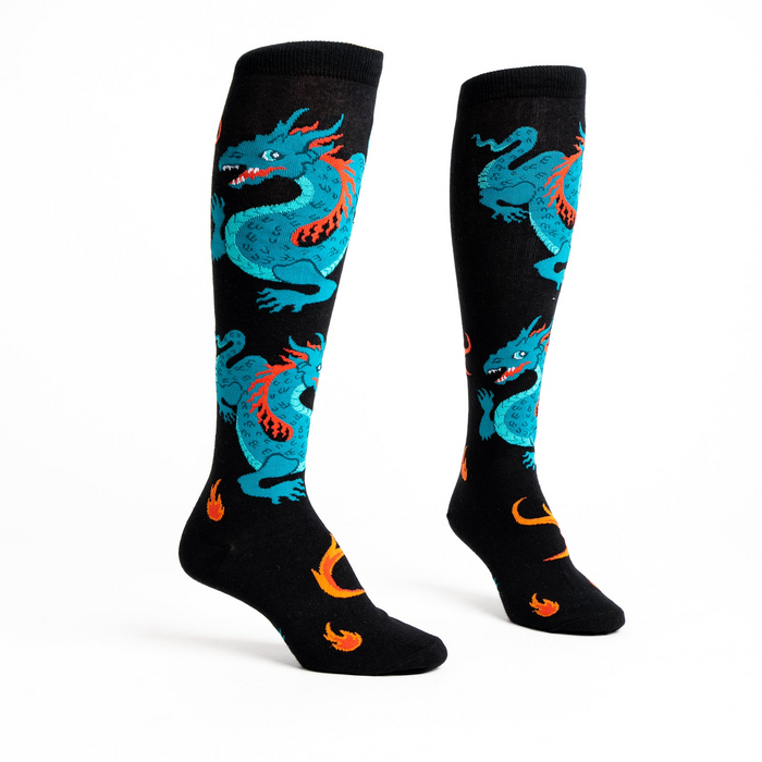 Flat lay studio shot of a pair of black knee-high socks with teal dragons and orange flames.