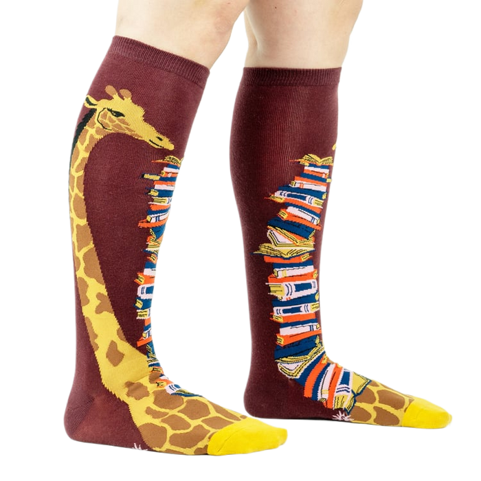 Knee-high socks on a model's legs, showcasing the giraffe and book design.