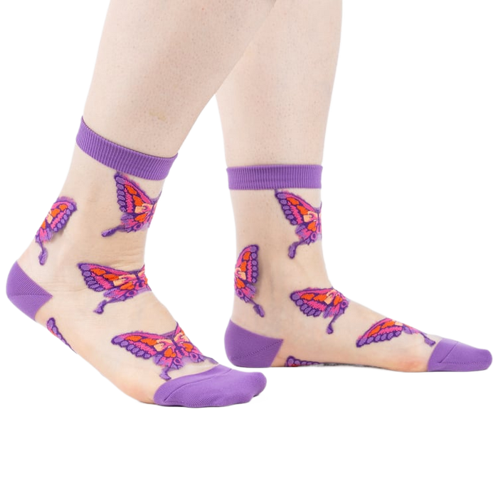 Sheer ankle socks in nude with purple cuffs and colorful butterfly designs.