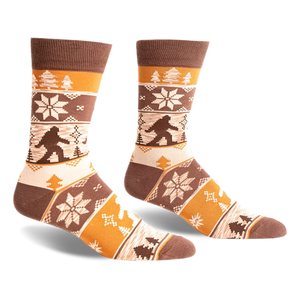 Brown, beige, and orange crew socks with a Bigfoot Fair Isle pattern.  Snowflakes and trees add to the wintery design.