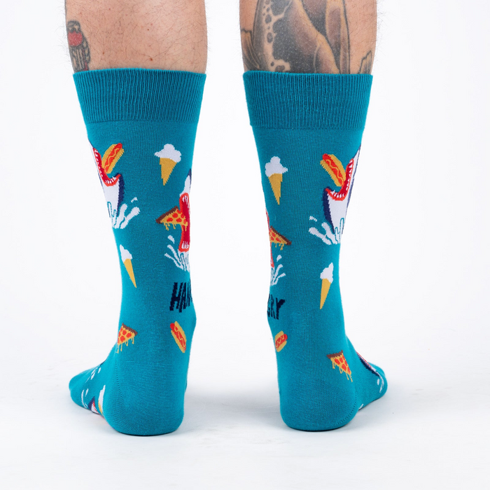 Back view of teal socks with shark and food design on a person's legs.