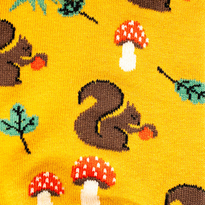 Close-up detail shot of the sock fabric showing the whimsical pattern of squirrels, mushrooms and leaves.