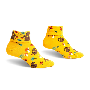 Pair of mustard yellow ankle socks featuring a playful pattern of squirrels, mushrooms, and leaves. Turn-cuff design.