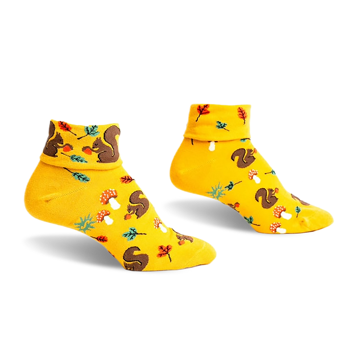 Pair of mustard yellow ankle socks featuring a playful pattern of squirrels, mushrooms, and leaves. Turn-cuff design.