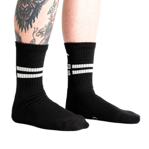Lifestyle shot showing black Bad Ass Athletic Ribbed socks on a person's legs.