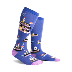 Pair of blue knee-high socks with a whimsical design featuring stacks of books, candles, and mushrooms. Purple accents at the cuff.