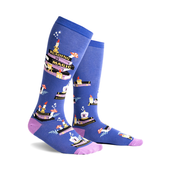 Pair of blue knee-high socks with a whimsical design featuring stacks of books, candles, and mushrooms. Purple accents at the cuff.