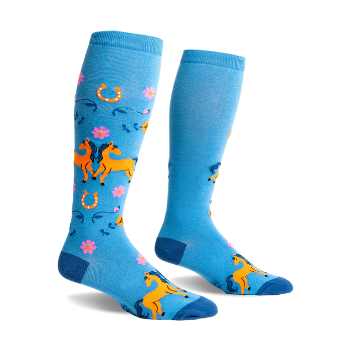 Pair of light blue knee-high socks with orange horses, pink flowers, and horseshoes. Fun, whimsical design.