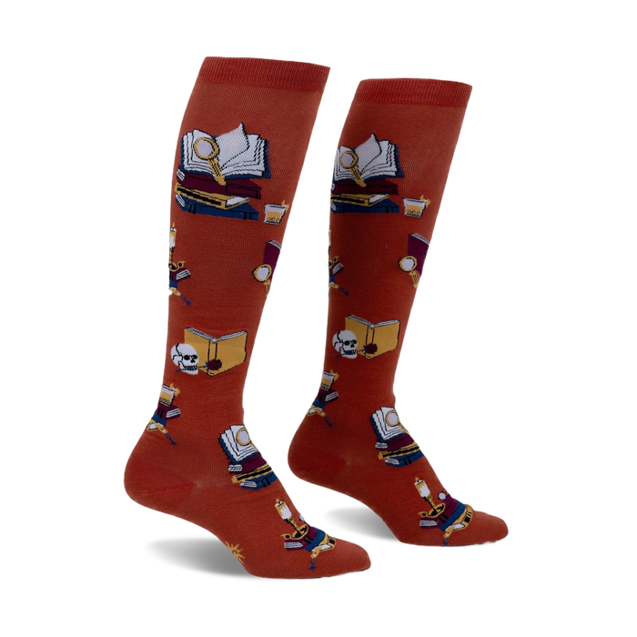Pair of burnt orange knee-high socks featuring a repeating pattern of books, magnifying glasses, and skulls.