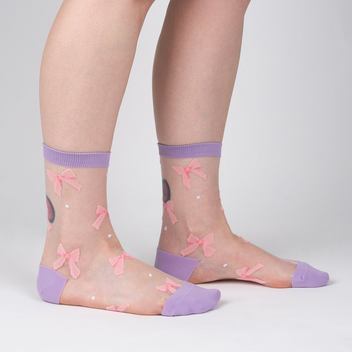 Lifestyle shot showing 'Wrapped in a Bow' socks on a model's legs, highlighting the fit and style.