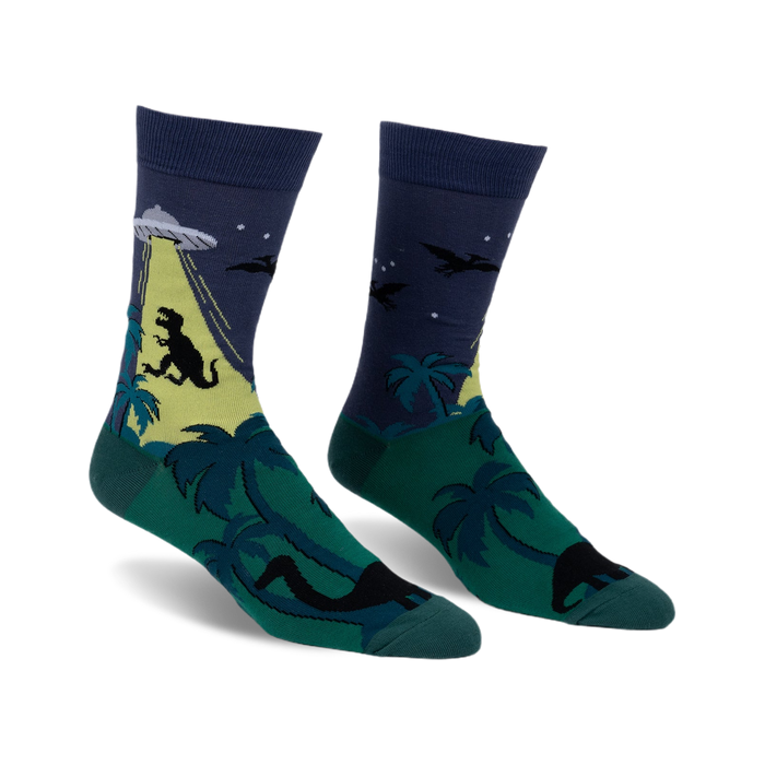 Crew socks in dark blue, green, and yellow. The design features a T-Rex, UFO, palm trees, and pterodactyls.