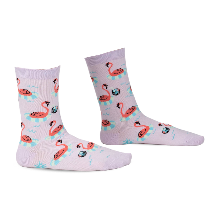 Pair of lavender crew socks with a fun flamingo design. Flamingos float on inflatable rings against a light purple background.