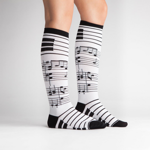 Woman's legs modeling the black and white musical note knee-high socks.