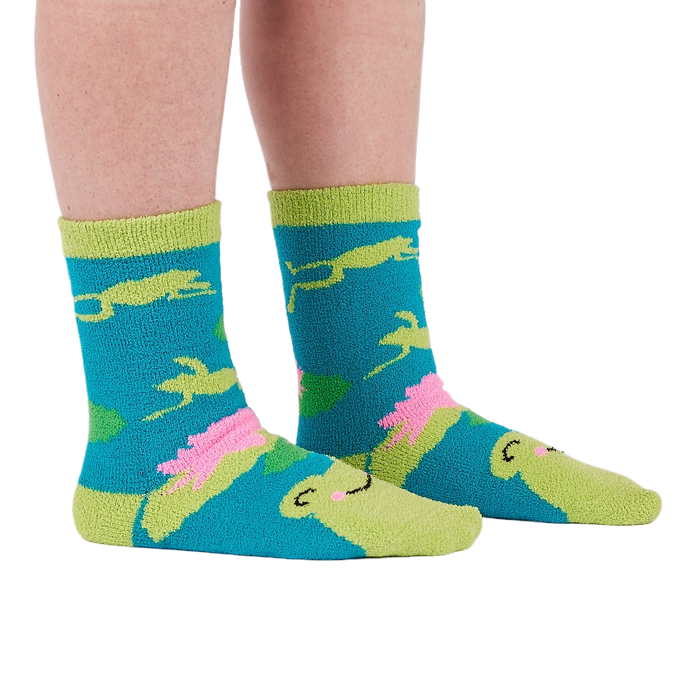 A person's legs and feet wearing the fuzzy teal blue slipper socks, shown from the side.