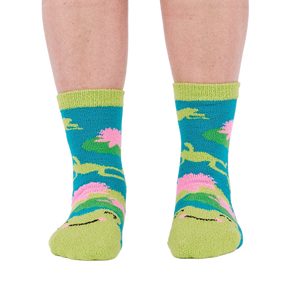 A person's legs and feet, viewed from the front, wearing the fuzzy teal blue slipper socks.